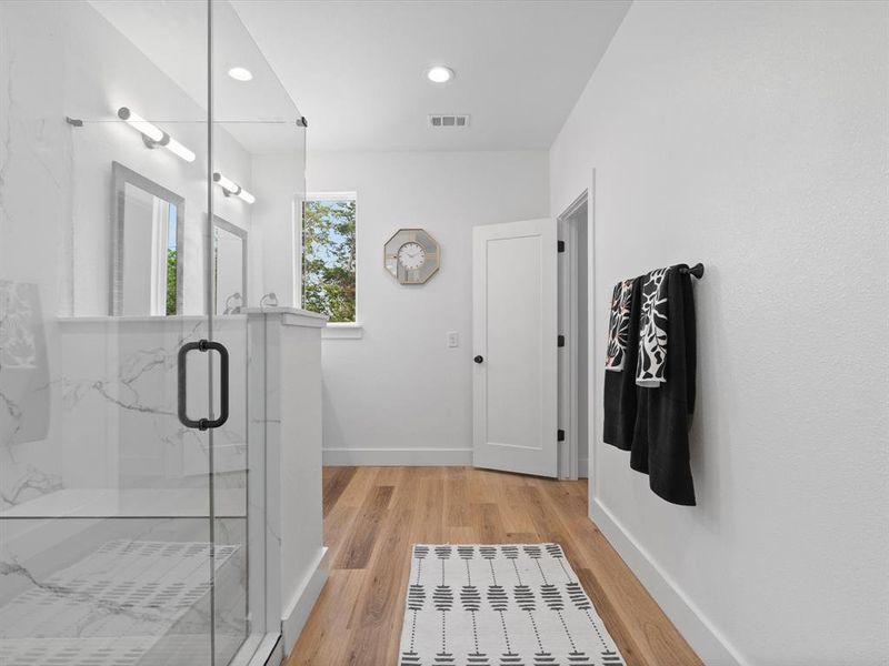 Full bathroom with visible vents, wood finished floors, baseboards, a marble finish shower, and recessed lighting