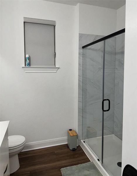 Enclosed shower with clear glass and matte black framing, featuring white-veined wall tile and a white shower pan Enclosed shower with clear glass and matte black framing, featuring white-veined wall tile and a white shower pan