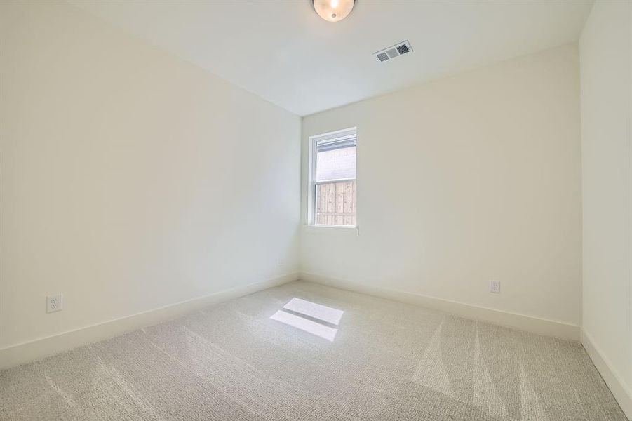 Empty room with carpet, visible vents, and baseboards