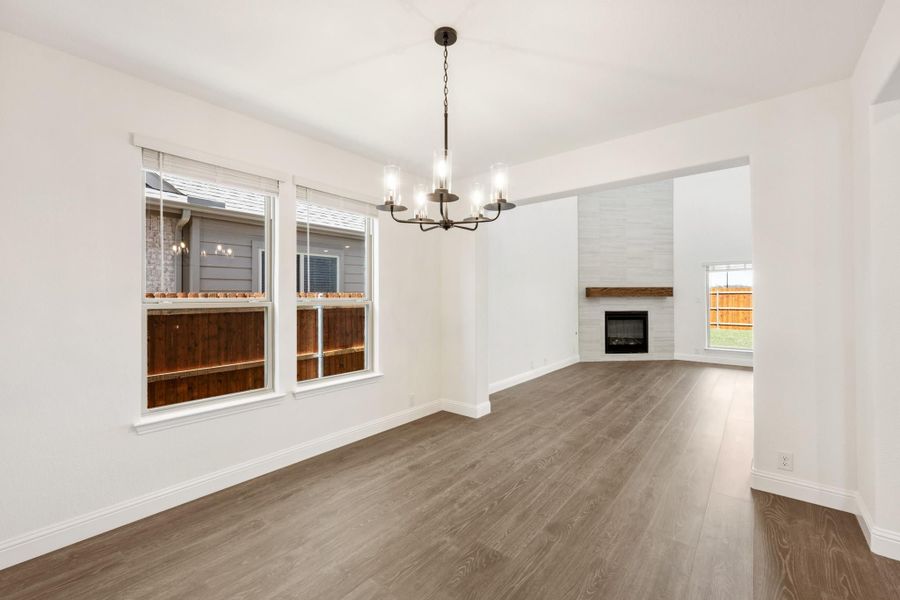 Open dining and living area with hardwood floors, chandelier, and shiplap fireplace with wood mantel