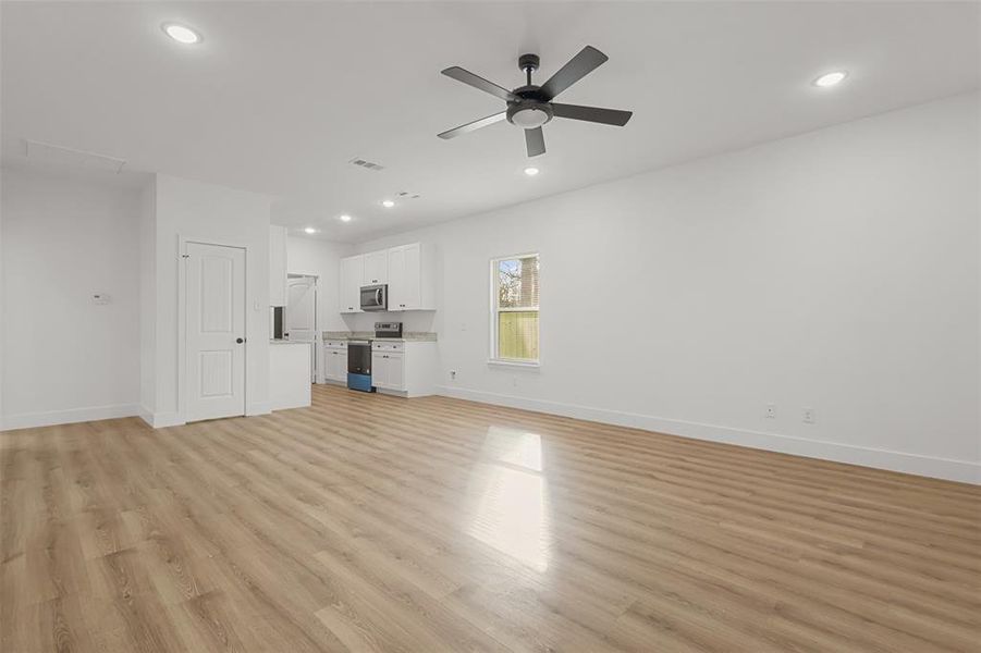 Unfurnished living room featuring ceiling fan and light hardwood / wood-style flooring