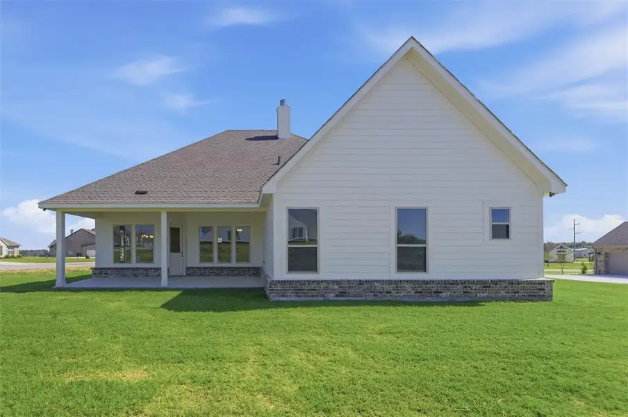 Rear exterior featuring a covered patio, white siding, and a stone accent foundation