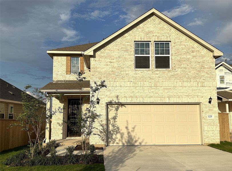 Traditional-style house featuring concrete driveway, fence, an attached garage, and brick siding Traditional-style house featuring concrete driveway, fence, an attached garage, and brick siding