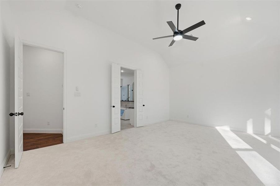 Unfurnished bedroom with lofted ceiling, carpet, ceiling fan, and ensuite bathroom