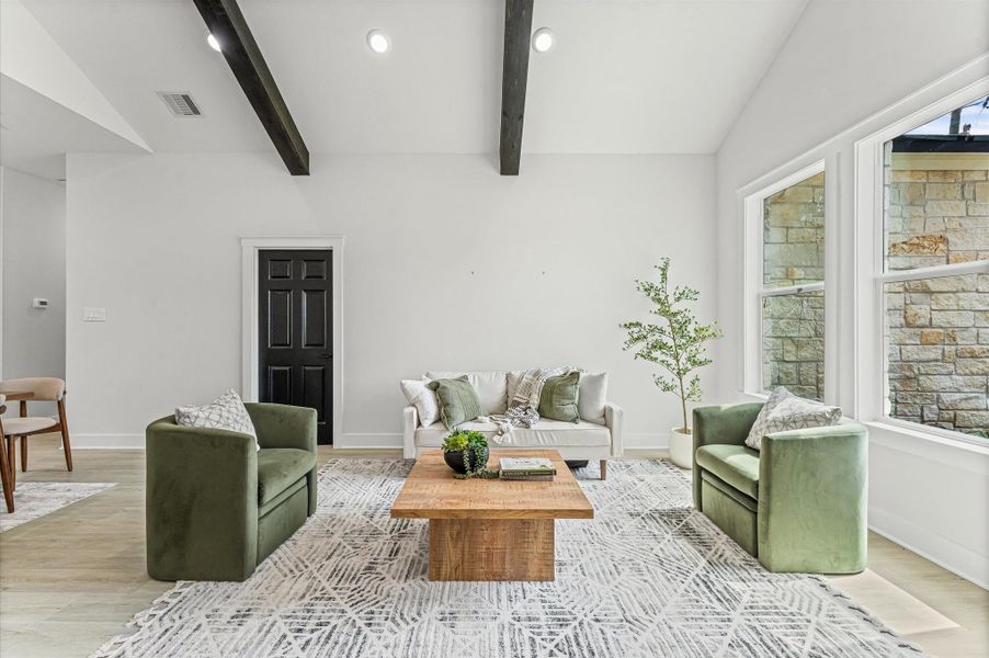 Bright and open living area with soaring cathedral ceilings and warm wood accents. High cathedral ceilings in living room. Photos are representative of the same floor plan built by this builder. Finishes will be the same or similar.