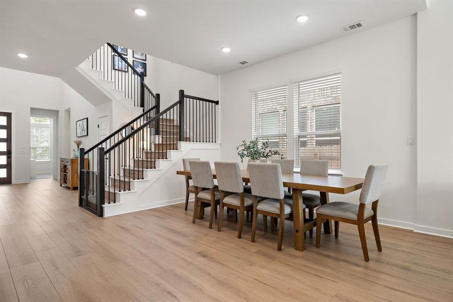 Elegant hardwood flooring flows throughout this luminous open-plan dining area and grand staircase. Elegant hardwood flooring flows throughout this luminous open-plan dining area and grand staircase.