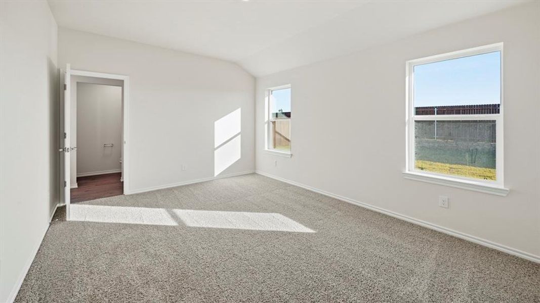 Empty room with carpet and lofted ceiling Empty room with carpet and lofted ceiling