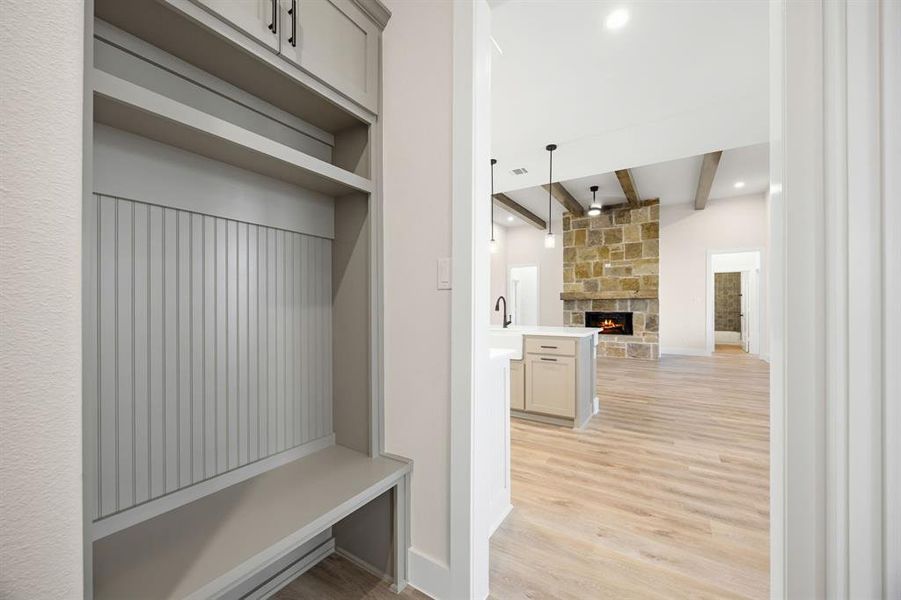 Built-in mudroom bench with beadboard backing, open shelving, and upper cabinetry