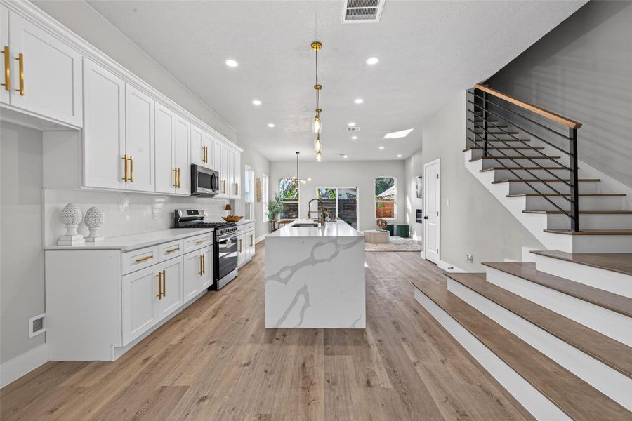 Your living space showcases wide-plank white oak–finish laminate flooring, recessed LED lighting, and a sleek floating staircase with wood treads and modern metal railing for a striking architectural statement.