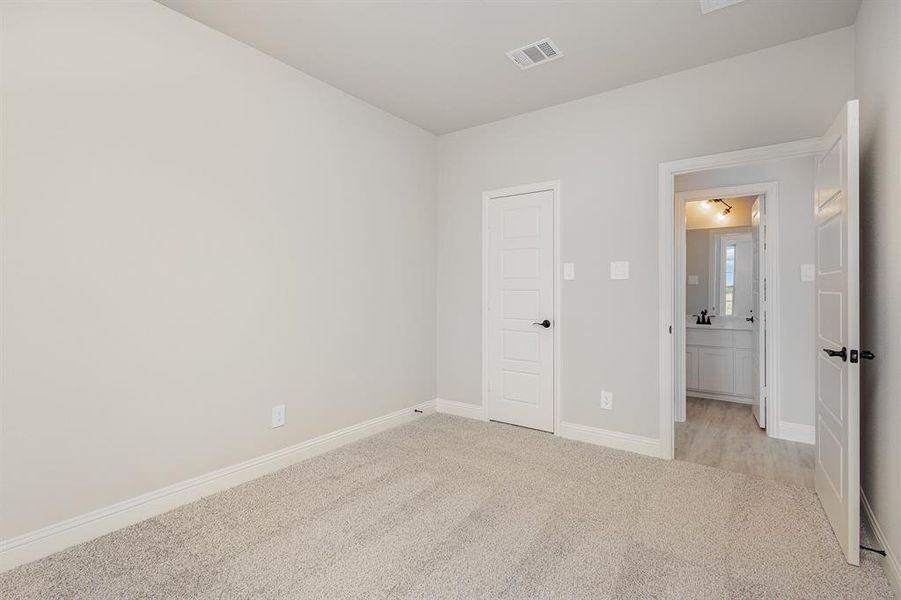 Unfurnished bedroom featuring light carpet and baseboards