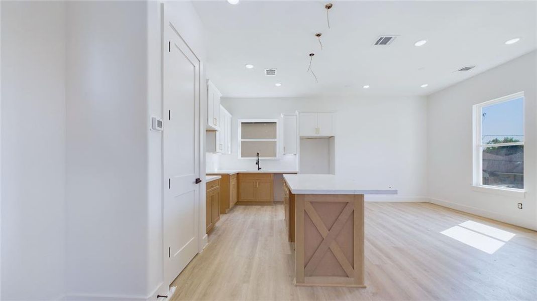 Alternate kitchen view reveals a dedicated dining area to the right. Recessed lighting, paired with an oversized window, allows light to flow effortlessly through the space.