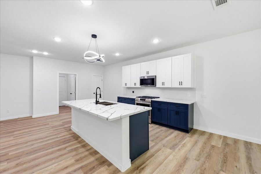 Modern chef's kitchen boasts a central island with breakfast bar seating and chic pendant lighting. Modern chef's kitchen boasts a central island with breakfast bar seating and chic pendant lighting.