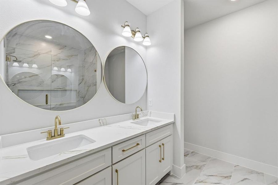 Bathroom featuring light marble finish flooring, a marble finish shower, double vanity, and recessed lighting