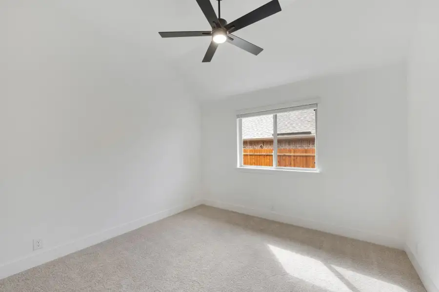 Empty bedroom with vaulted ceiling, black ceiling fan, carpet flooring, and single window