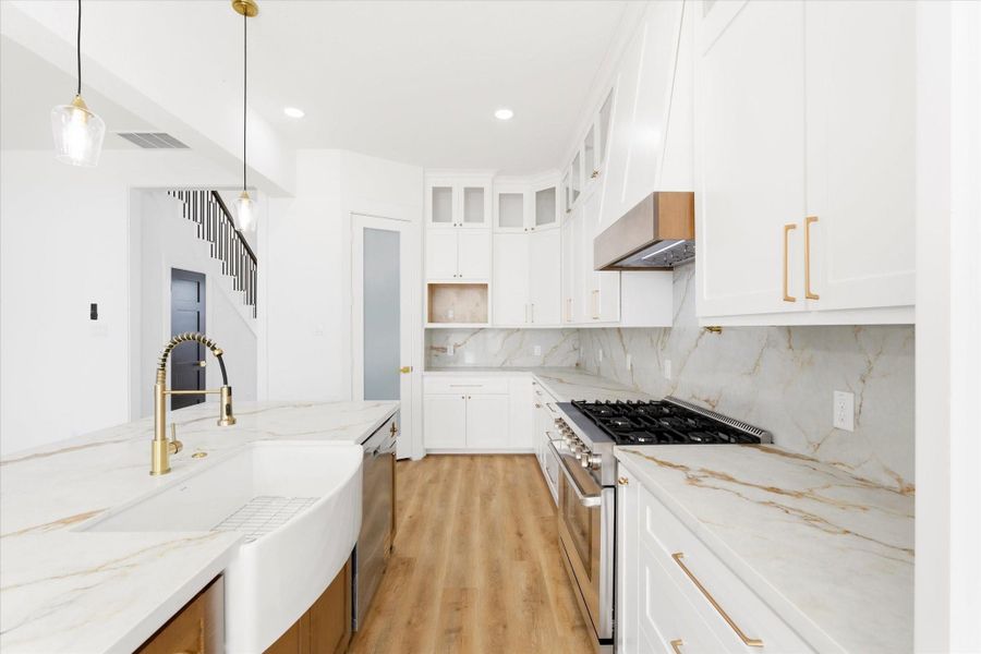 A stunning kitchen with custom solid wood cabinetry, thoughtfully designed with dedicated storage for a built-in microwave, spice rack, utensil holder, trash bin, and more.
