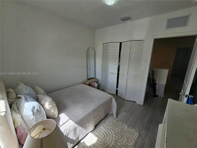 Room featuring light wood-finish flooring and a built-in closet with white louvered bifold doors