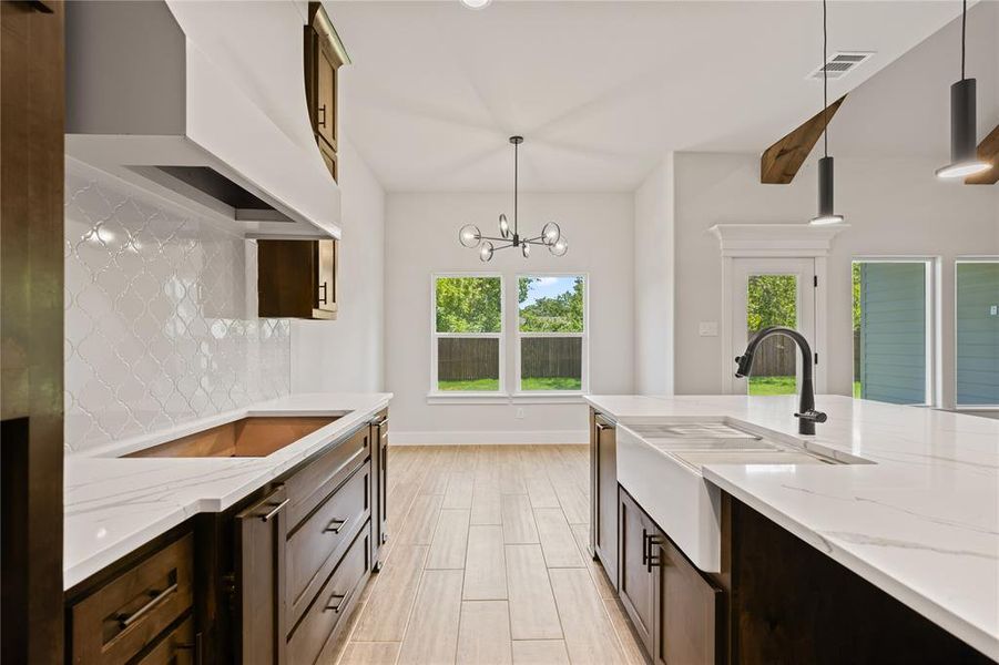 Contemporary kitchen island featuring a white apron-front sink, dark cabinetry, and a matte black faucet
