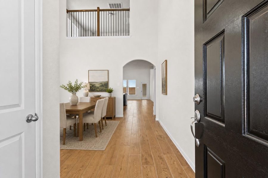 Step inside to the bright and welcoming entry foyer featuring beautiful wood looking tile flooring and soaring ceilings that create an open and airy first impression. The entry hallway leads seamlessly toward the main living areas while offering a view of the open concept layout and second floor overlook above. *Photo is Virtually Staged*