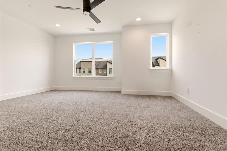 Empty room featuring light colored carpet, plenty of natural light, and ceiling fan