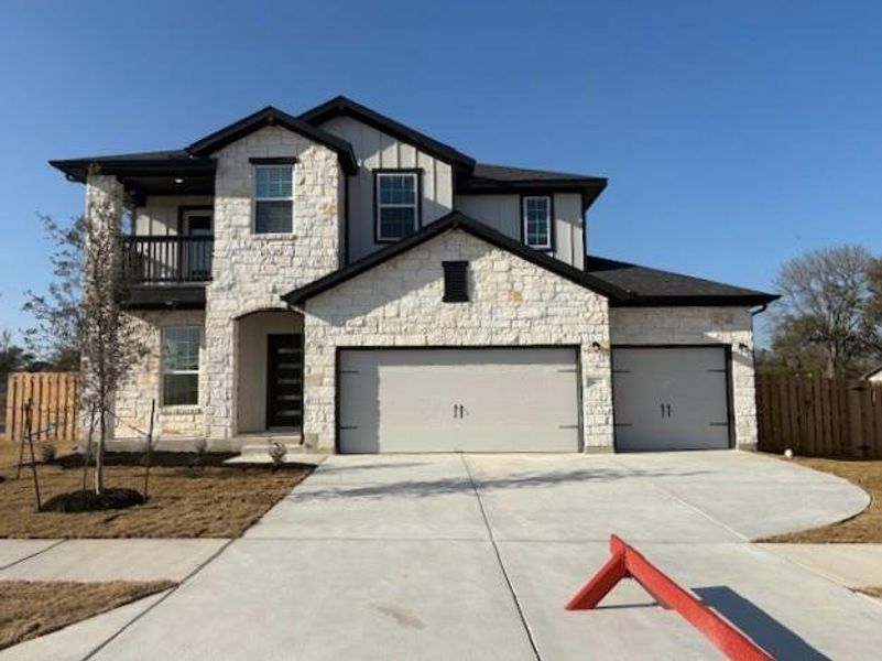 View of front of property featuring an attached garage, a balcony, fence, concrete driveway, and board and batten siding