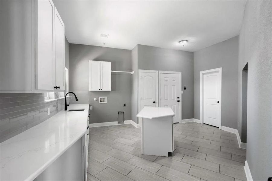 Laundry room with hookup for an electric dryer, hookup for a washing machine, wood tiled floors, and cabinet space