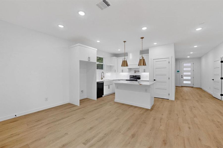 Kitchen with a center island, white cabinetry, hanging light fixtures, light wood-type flooring, and recessed lighting Kitchen with a center island, white cabinetry, hanging light fixtures, light wood-type flooring, and recessed lighting