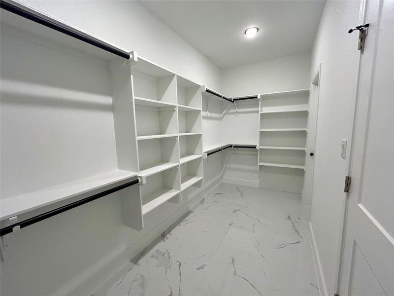 Primary bedroom walk-in closet with tiled floor.