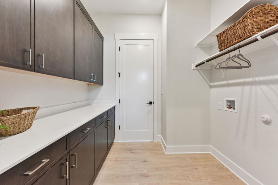 Laundry area with light wood-style flooring, cabinet space, and washer hookup