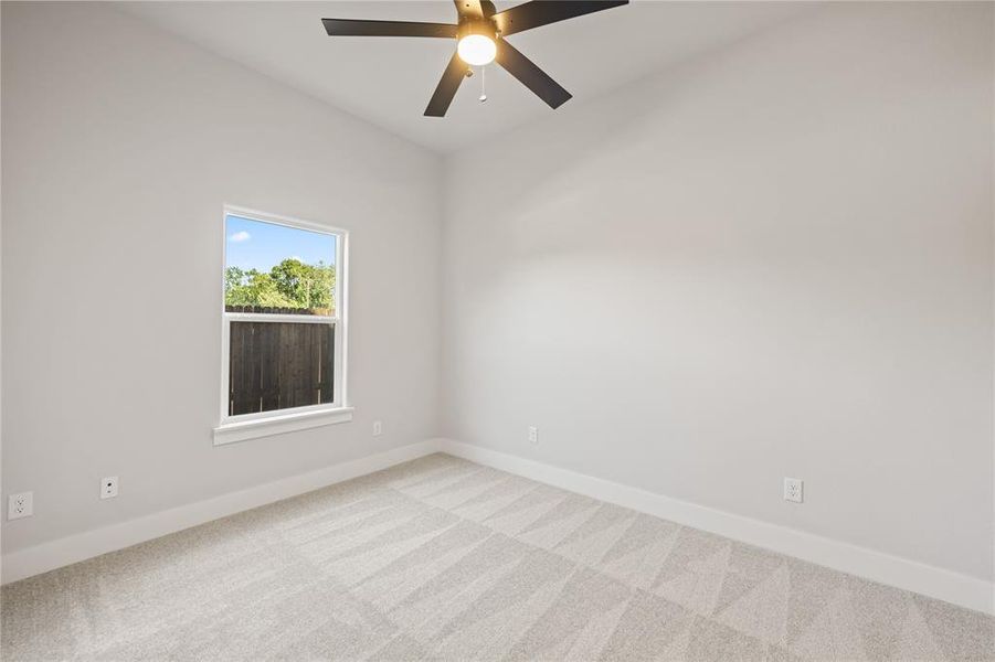 Bright room with a window providing natural illumination, ceiling fan, neutral wall tones, and patterned carpet flooring