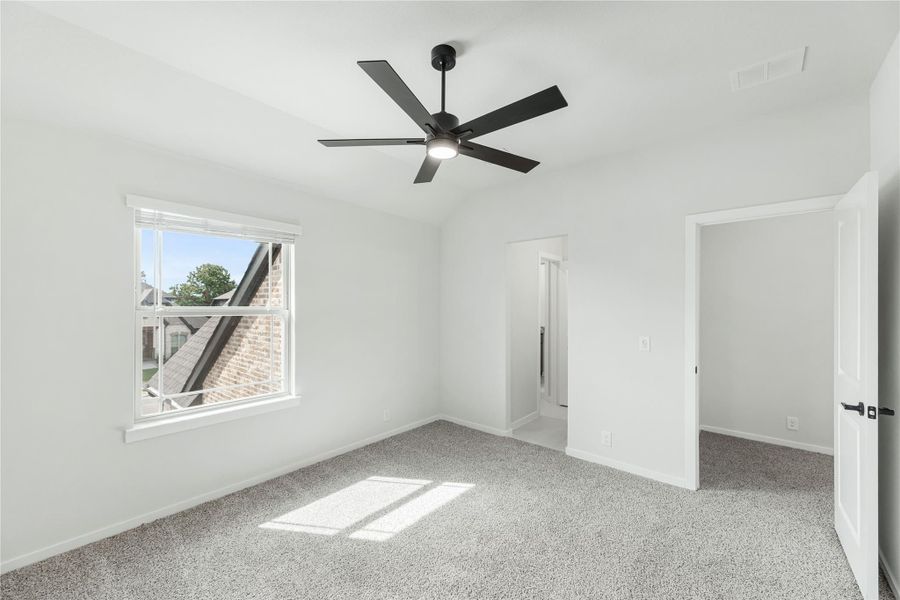 Empty bedroom with gray carpet, black ceiling fan, and white walls with two doorways