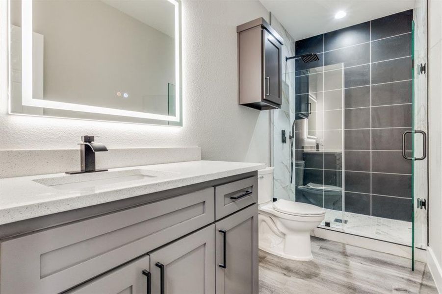 Bathroom featuring vanity, wood-type flooring, an enclosed shower, and toilet