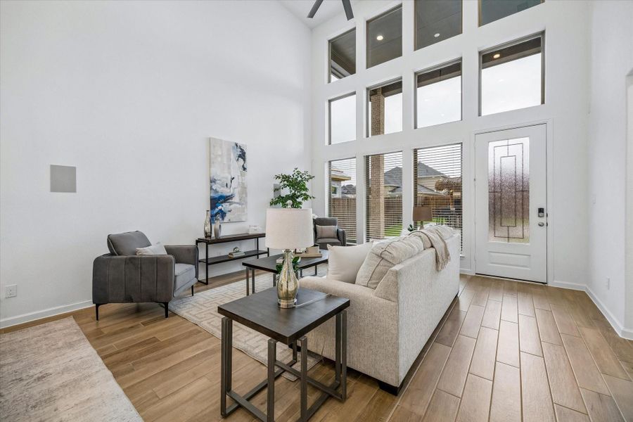 The family room feels both welcoming and impressive with a soaring 19’ ceiling, stacked windows, fresh finishes, and beautiful wood-look tile that carries through the main living areas.