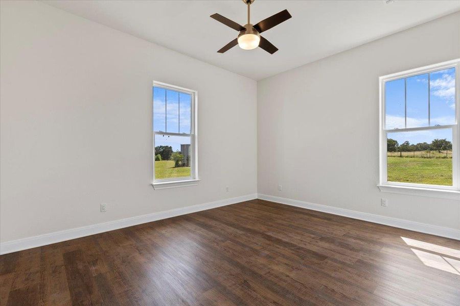Spare room with healthy amount of natural light, dark wood-type flooring, and ceiling fan