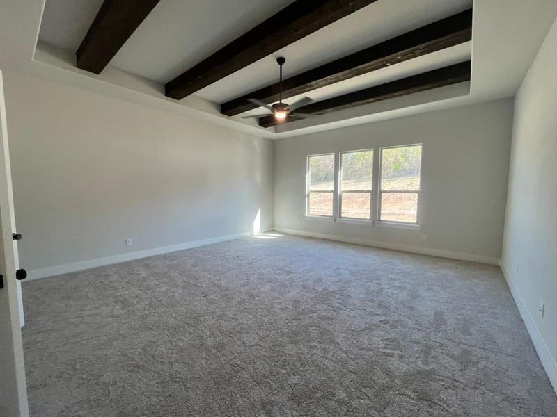 Spare room with carpet flooring, beamed ceiling, and ceiling fan