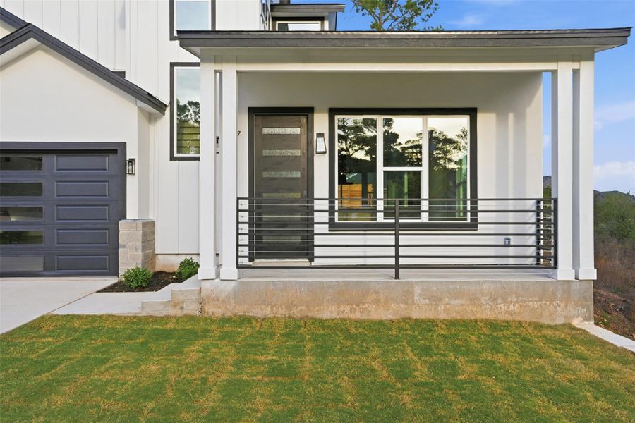 Property entrance with a lawn, board and batten siding, a porch, driveway, and an attached garage