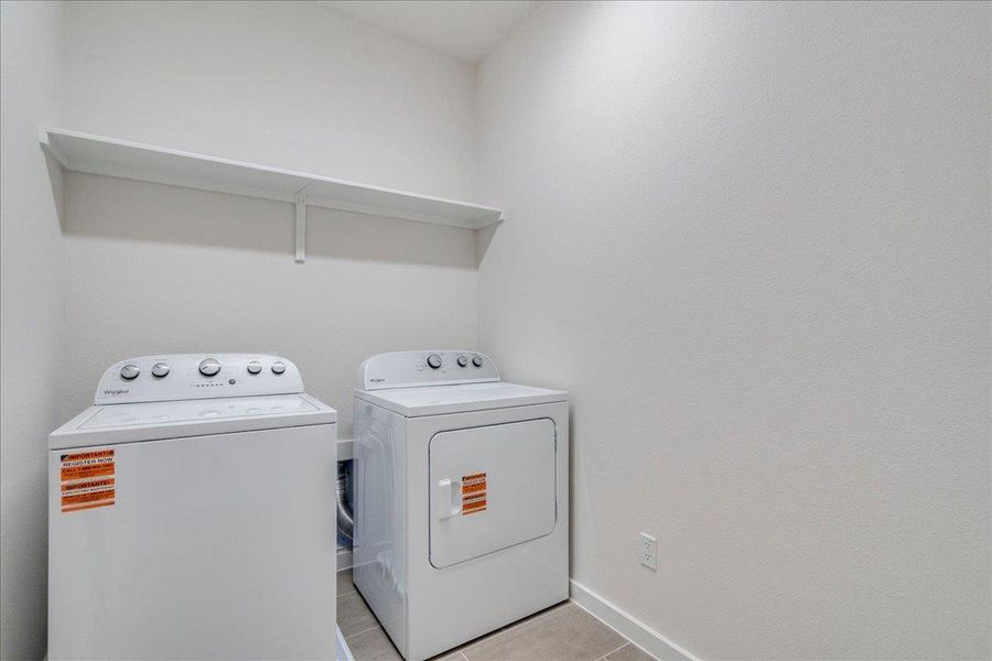 A dedicated laundry space featuring a washer and dryer with convenient overhead shelving.