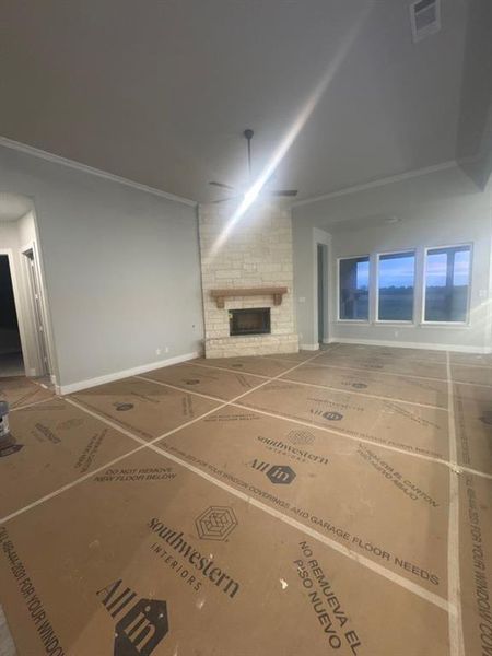 Unfurnished living room featuring a fireplace, ornamental molding, and ceiling fan