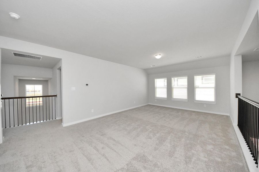 Come upstairs and enjoy a day of leisure in this fabulous game room! This is the perfect hangout spot or adult game room! Features plush carpet, high ceilings, custom paint and windows for plenty of natural light. Sample photo of completed home with similar floor plan. Actual colors and selections may vary.