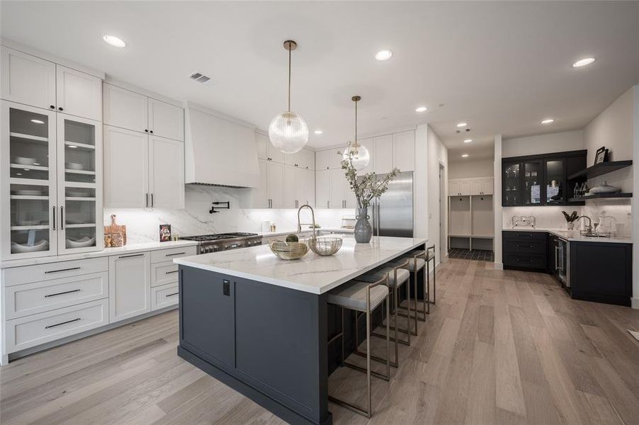 The open gourmet kitchen elevates every culinary endeavor with sleek custom cabinetry trimmed with undercabinet lighting and gorgeous Calacatta marble countertops.