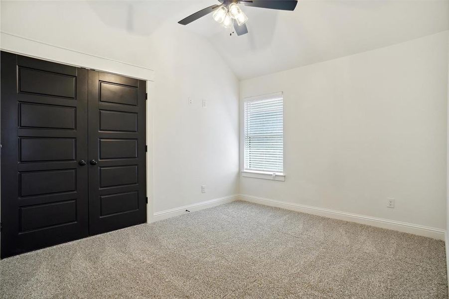 Unfurnished room featuring vaulted ceiling, carpet, and ceiling fan