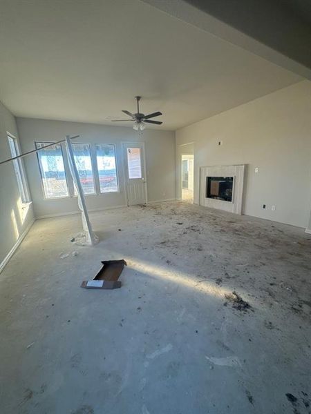 Unfurnished living room with ceiling fan and a fireplace