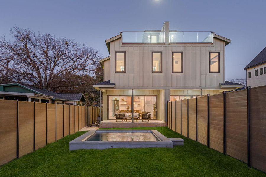 Back of house at dusk with board and batten siding, a patio, and a fenced backyard