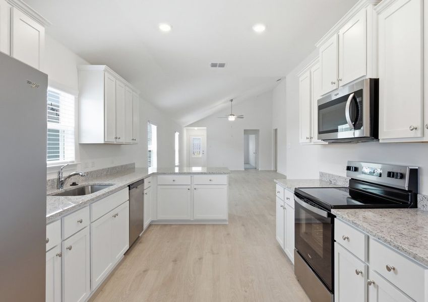Kitchen featuring a granite island, white cabinetry, and stainless steel appliances. Kitchen featuring a granite island, white cabinetry, and stainless steel appliances.