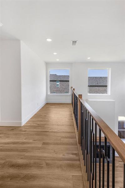 Hallway featuring a healthy amount of sunlight and light hardwood / wood-style flooring