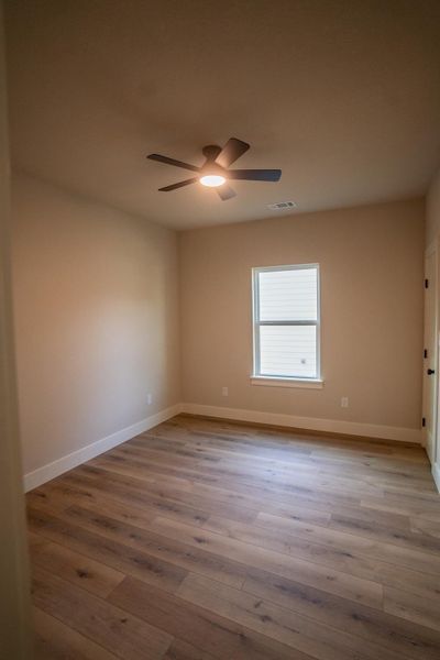 Empty room featuring visible vents, baseboards, a ceiling fan, and wood finished floors