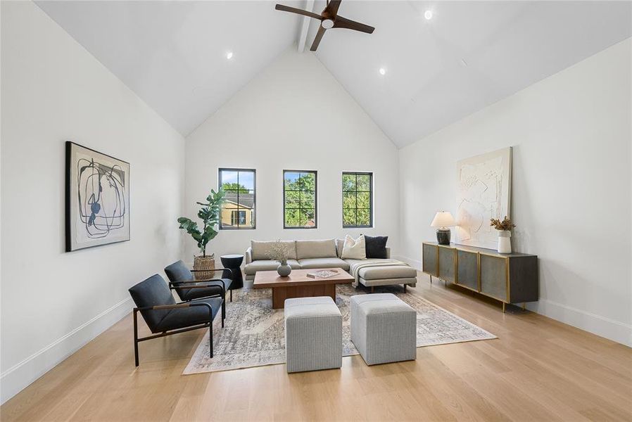 Vaulted ceiling living space featuring light wood-finish flooring, recessed lighting, and a dark wood ceiling fan