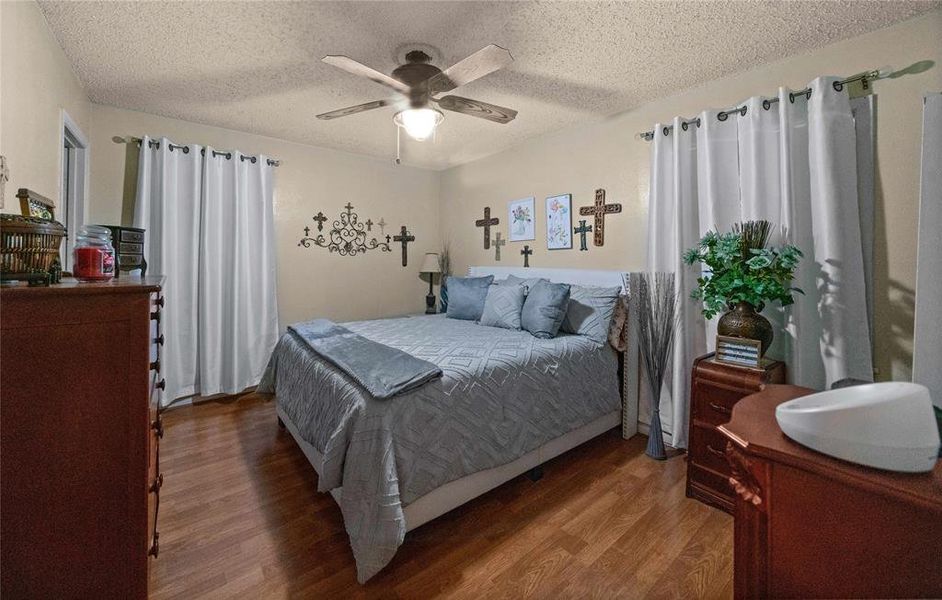 Bedroom with wood finished floors, a textured ceiling, and a ceiling fan