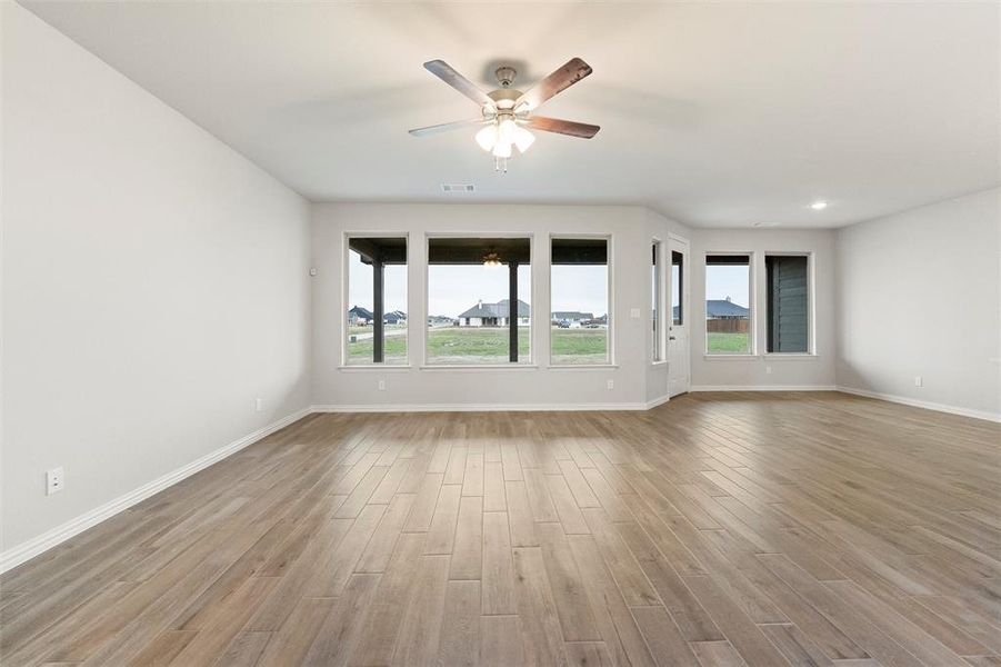 Spare room featuring light wood finished floors, plenty of natural light, and a ceiling fan Spare room featuring light wood finished floors, plenty of natural light, and a ceiling fan