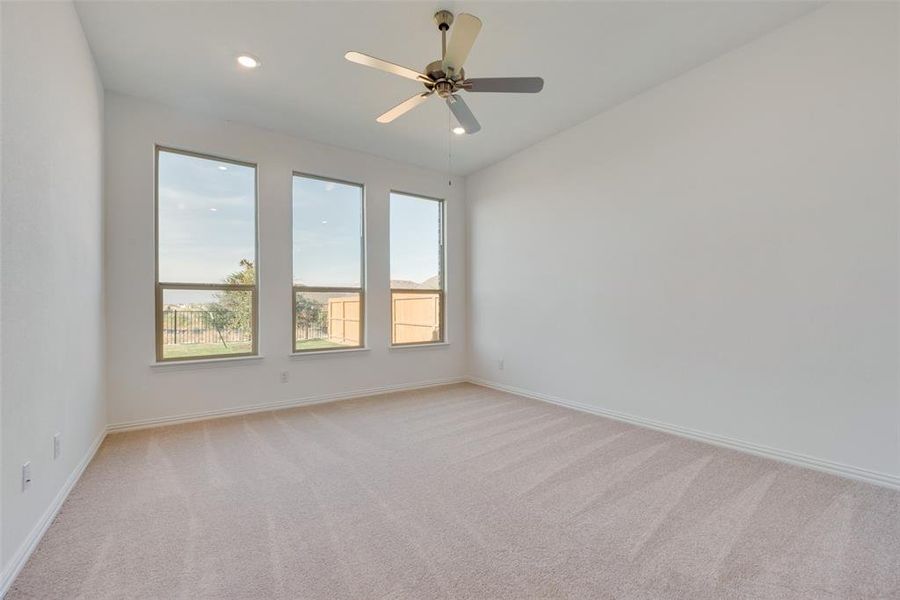 Empty room featuring light colored carpet and ceiling fan