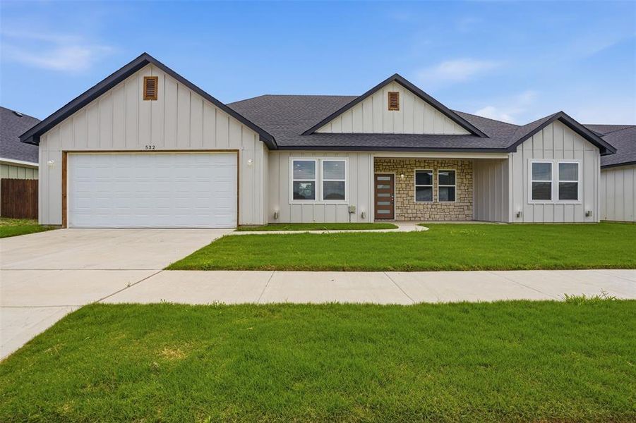 Contemporary one-story residence featuring light vertical siding and stone accents